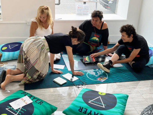 Four people including Abigail Simon and Marina Zurkow play The Iceberg on the floor of a gallery