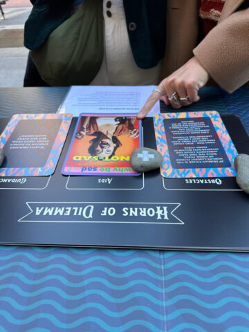 a hand points to a card from The Iceberg