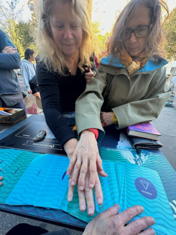 Two people touch hands while playing The Iceberg